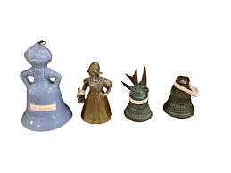 Lot - Lot of 18 bells. Blue ceramic old maid bell. Heavy brass Dutch girl bell. San Juan Capistrano mission souvenir bell with bird handle. Santa Barbara mission souvenir bell. Three Mexican