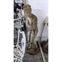 A weathered garden concrete statue of a man in a winter coat ...