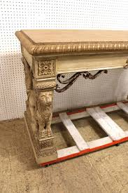 Sold at Auction: Elaborate standing lion console table in manner of Maitland Smith, paint decorated and highly carved and ornate with metal scroll accents and stone finish style top, 64"l x 26"w x