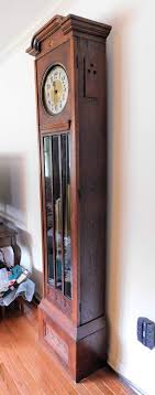 Lot Detail - Mission Style Oak Tall Case Clock - Weight Driven - Brass Emblem Inside - Missing Glass on Face - 1 Side Piece Has Been Repaired - 82" tall 18" by 10"