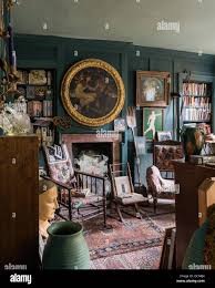 Quirky teal coloured wood panelled bedroom filled with diverse objects - oriental carpets, antique chairs, gilt framed art Stock Photo - Alamy