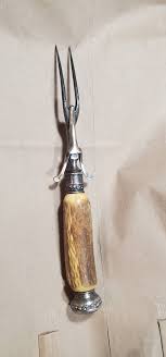 What is the purpose of the hinged hook on a carving fork?