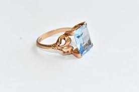 Sold at Auction: Vintage English 9ct Gold and Blue Topaz Dress Ring - set with large emerald cut solitary blue topaz in four claw raised setting with bow motif to shoulders, English