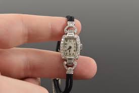 Lot - Tiffany & Co. platinum and diamond vintage ladies wristwatch. Set with 42 round diamonds and 8 graduated baguettes. Clasp marked PLAT. Monogrammed MGC on underside. Band measures approx 1.75in diameter. Watch running ...