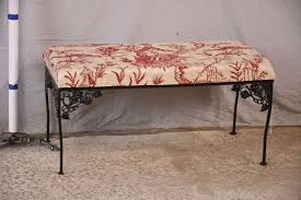 Ornate black iron bench with red and off-white toile fabric ...